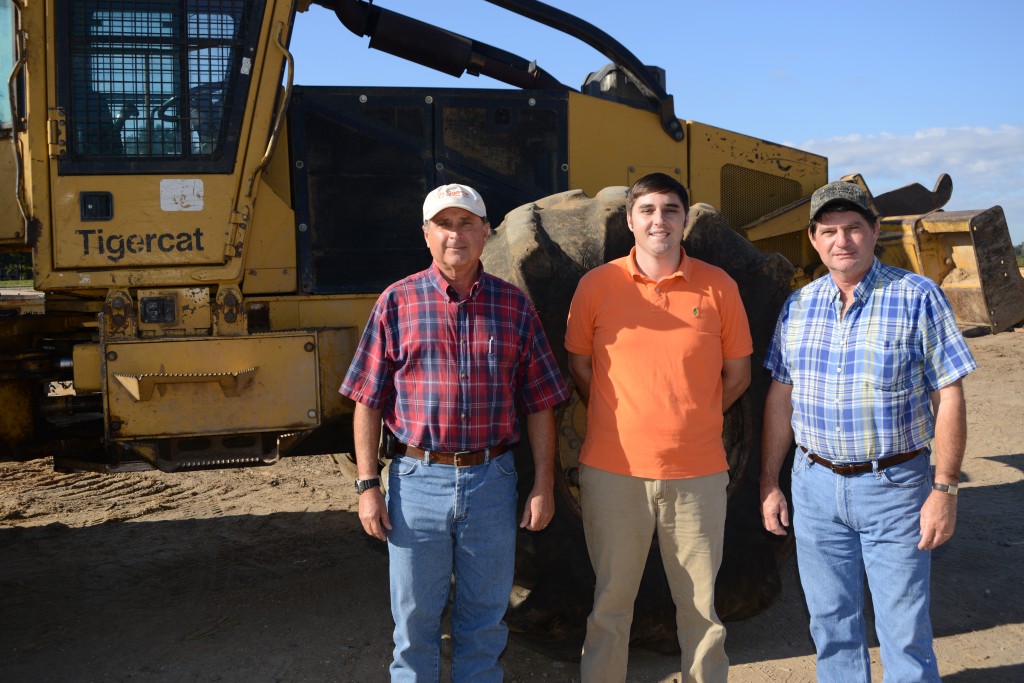 B&G Equipment sales specialist Cleve Altman, general manager Manuel Henderson and Glenn Henderson. stand together in front of a Mackolines Machines & Hire skidder.