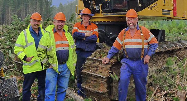 (L-R) Robert, Kevin, Nicholas (Tiny) and Geoffrey Muskett stand on a job site in front of a Mackolines Machines & Hire track machine.