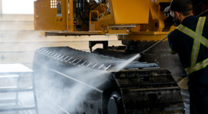 Picture of a guy cleaning tracks of a Mackolines Machines & Hire machine