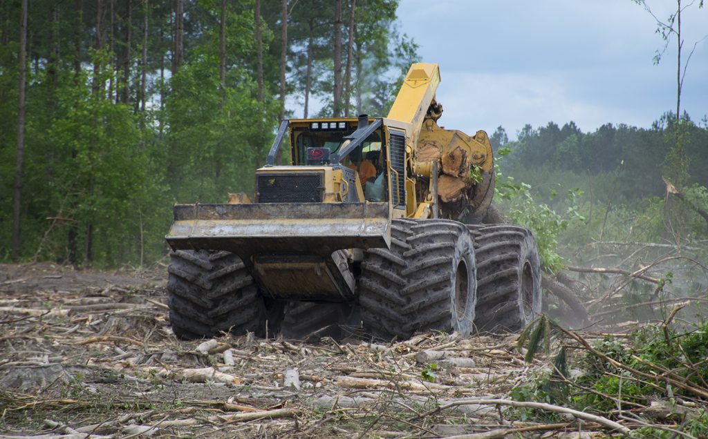 A Mackolines Machines & Hire 4-wheel skidder with extra wide flotation tires hulling a load of wood in it's grapple.