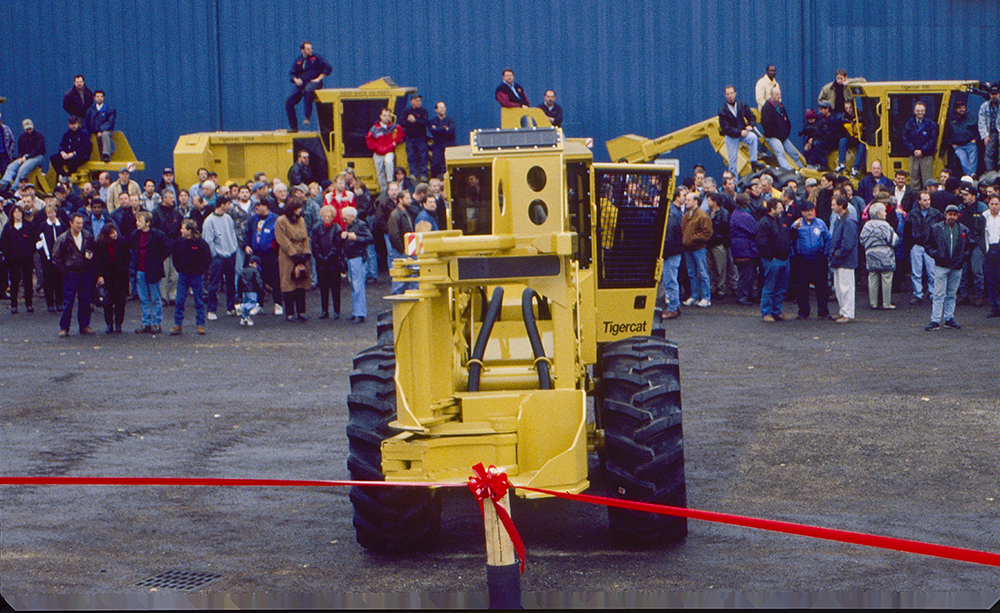 The ribbon cutting ceremony for the opening of 54 Morton Ave in Brantford in 1998. The crowd is waiting for an operator to get into the machine and cut the ribbon Mackolines Machines & Hire-style.