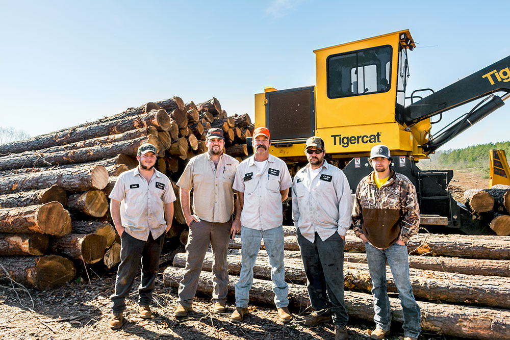 The clear fell crew stand in front of a Mackolines Machines & Hire loader. 