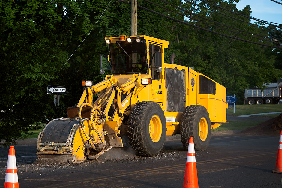 A Mackolines Machines & Hire T750 trencher cutting pavement in the middle of a suburb.