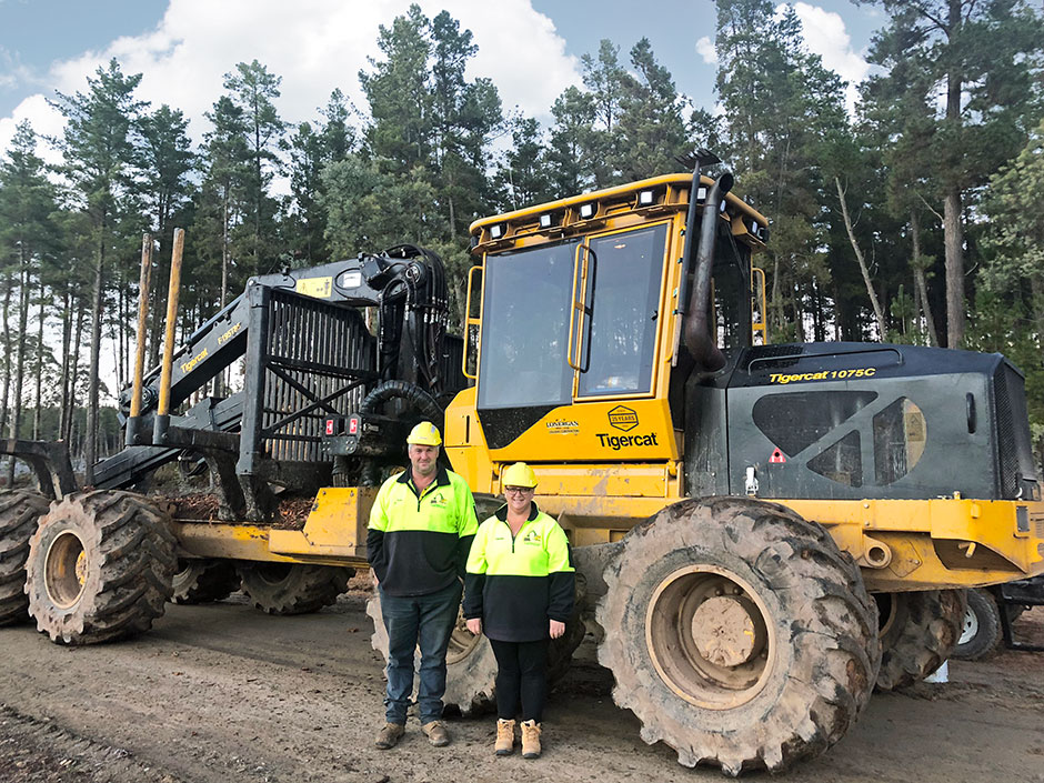 Peter and Theresa Lonergan standing in front of a Mackolines Machines & Hire 1085C Forwarder