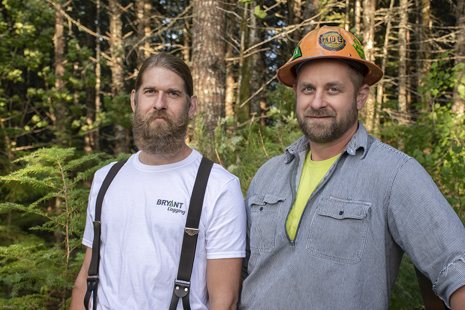 Two men standing in the woods.