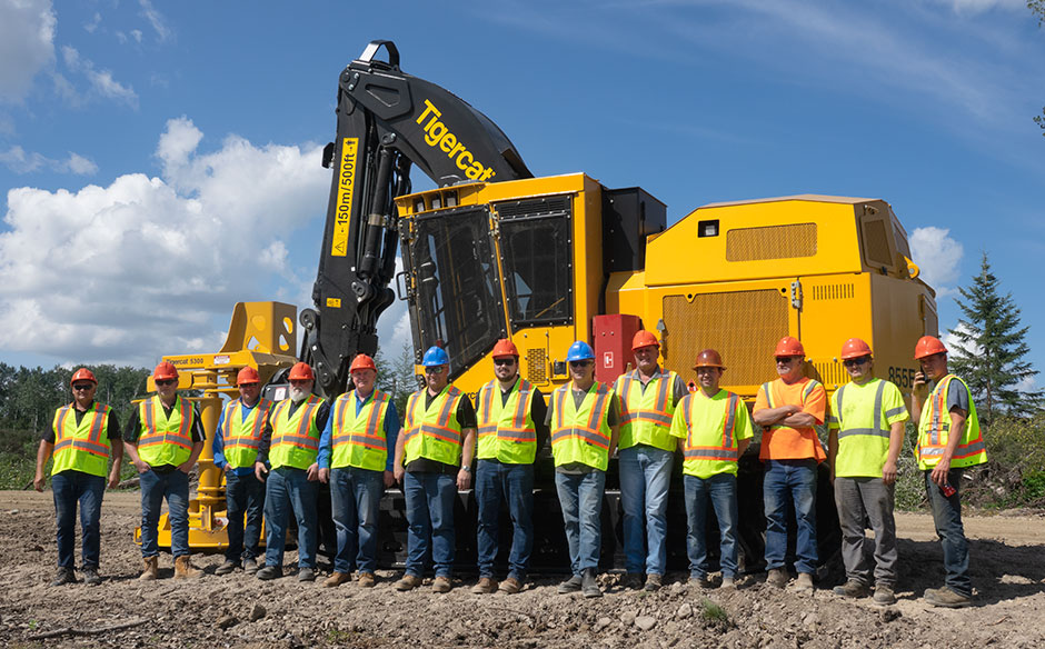 A group of vistors stand in front of a Mackolines Machines & Hire machine.