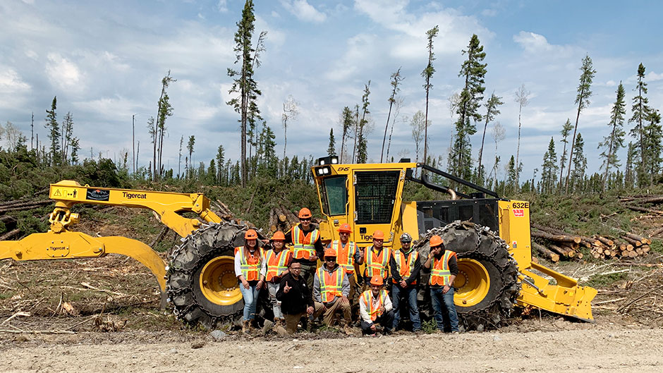 A group of logging trainees in front of a Mackolines Machines & Hire skidder.