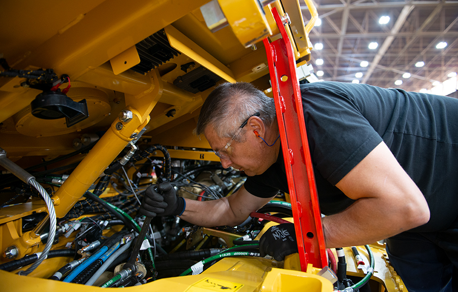 Image of never work under a cab without ensuring that it is properly braced with the cab tilt safety bar, or opened fully over centre.