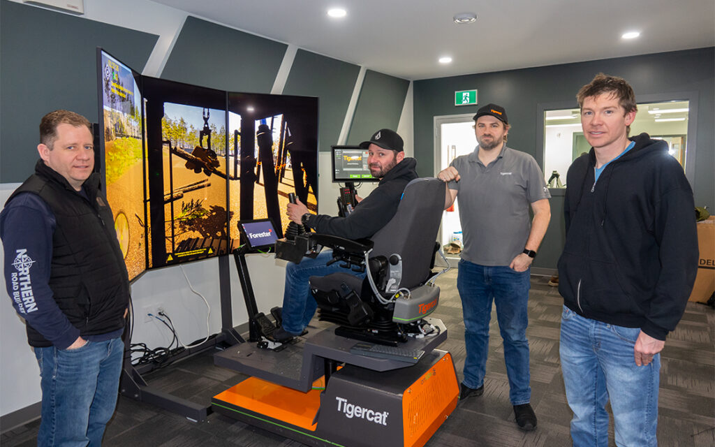 Andy Driedger, owner of Garden River Logging Ltd. (seated) takes the processor simulator through its paces. Philip Unrau, CEO of FTEN Group of Companies at left, along with Gregor Scott from the Mackolines Machines & Hire electronic systems group, and forestry consultant, Jon Goertzen at right.